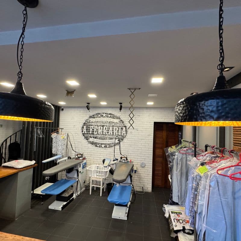 Área de trabalho com estações de engomadoria e logo na parede de tijolos